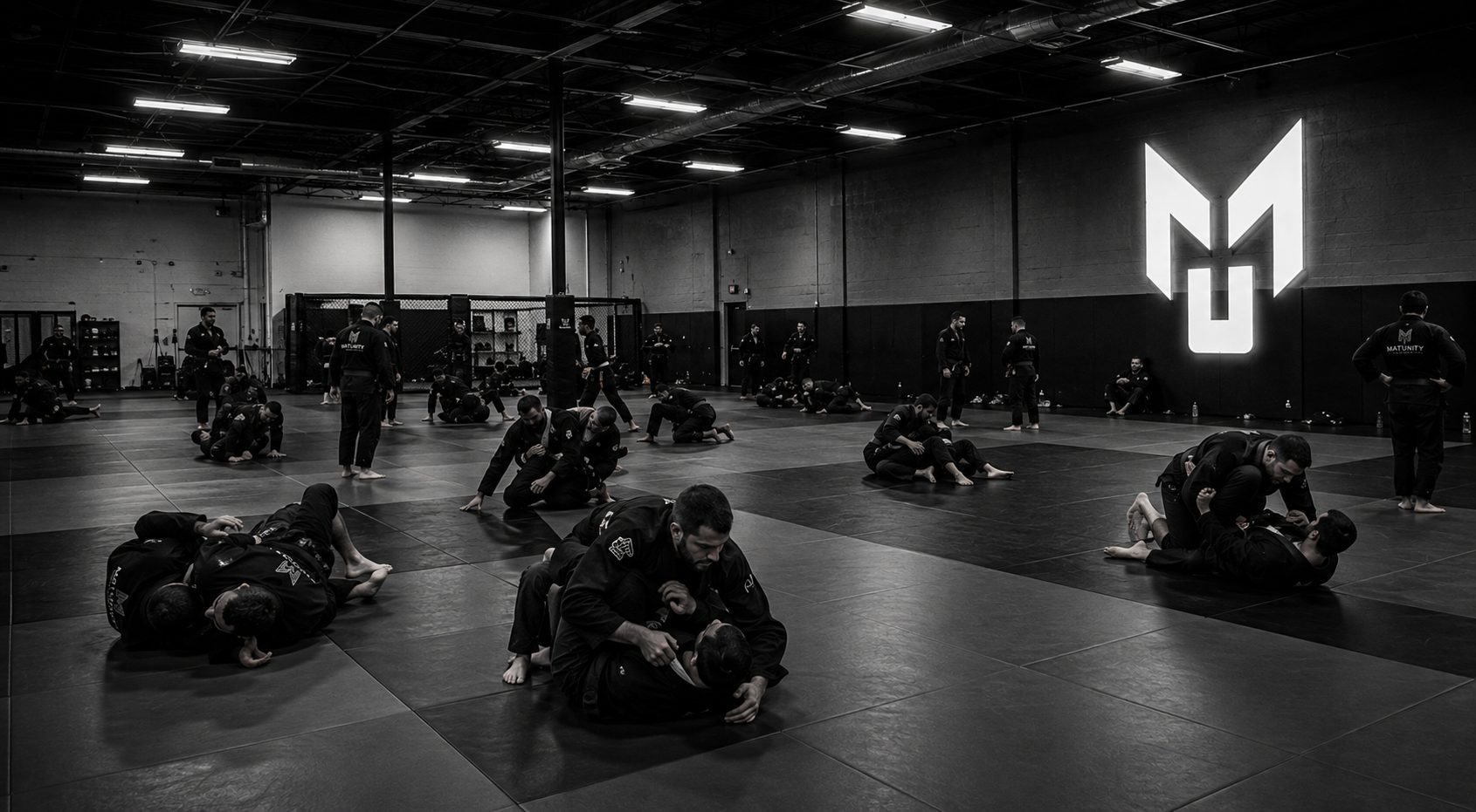 A full academy mat with dozens of athletes rolling in gis